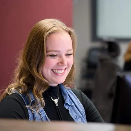 Front desk staff, smiling while looking at a computer
